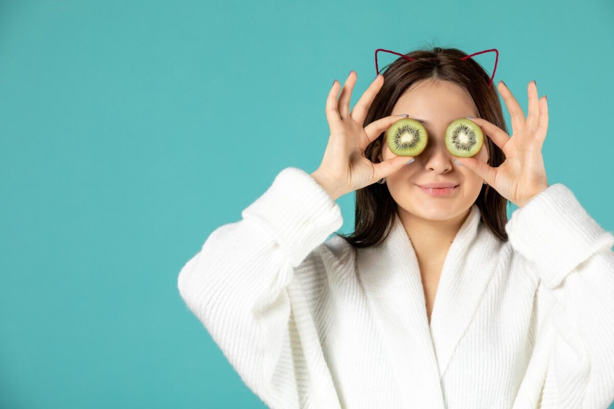 front-view-young-female-bathrobe-holding-kiwi-slices-blue-background_140725-149844
